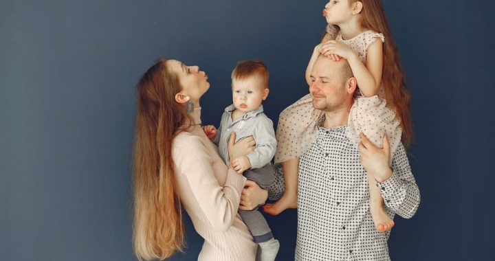 Portrait of a joyful family with parents and kids showing love and affection against a blue background.